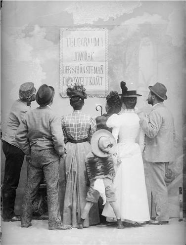 Das Motiv der Veranstaltung, die Studioaufnahme von ca. 1900 - Sieben Personen vor einem Plakat - Foto: Waldmüller/Bestand Fotostudio Waldmüller/Amt für Film und Medien