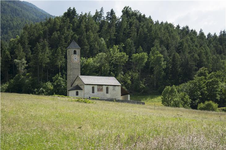 Die Kirche St. Johann mit dem ummauerten Friedhof liegt malerisch und weithin sichtbar in Waldnähe erhöht über Prad: Nun hat die Landesregierung einen Denkmalschutz für das Umfeld der Kirche beschlossen. (Foto: LPA/Udo Thoma)