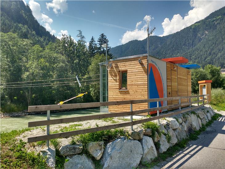 Auge auf die Rienz: die erneuerte und erweiterte Pegelmessstelle bei Vintl vom Radweg aus gesehen, über dem Wasser schwebend der gelbe Messflügel (Foto: Landesamt für Hydrologie und Stauanlagen)