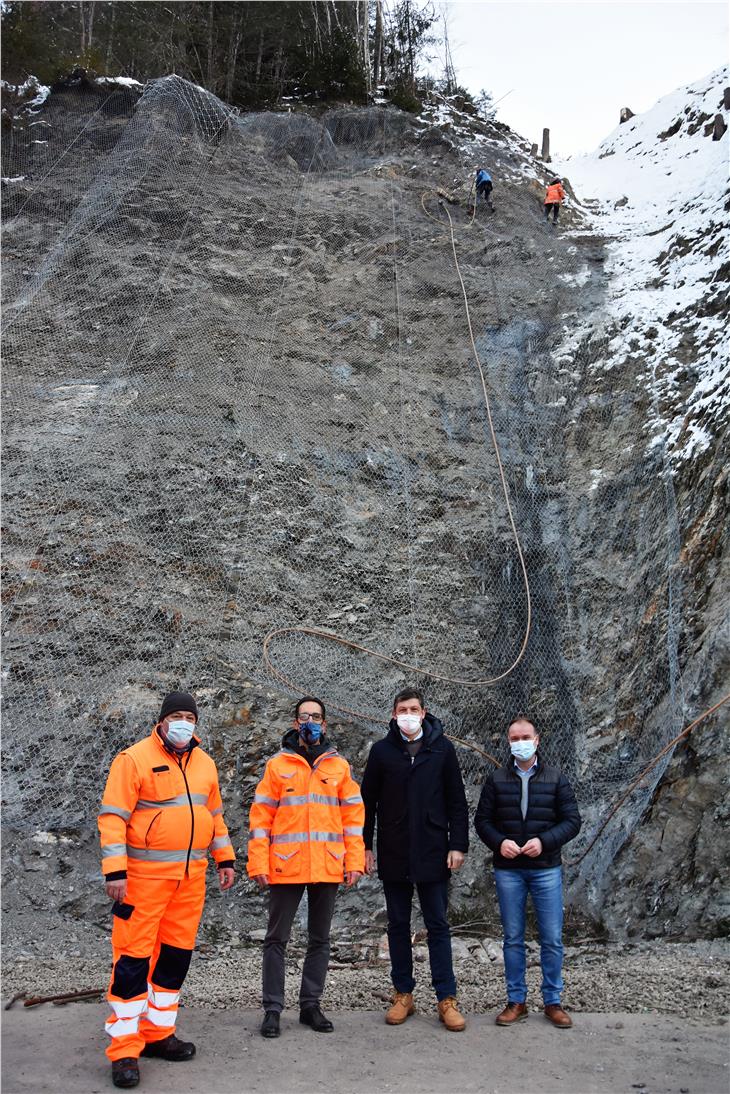 An der Steilstelle wurde 10.000 Kubikmeter Material entfernt. Nun sichern die Felskletterer die Stelle. Patrick Kostner und Marco Losso (Straßendienst), LR Daniel Alfreider und BM Stefan Leiter begutachten die Arbeiten. (Foto: LPA/Angelika Schrott)