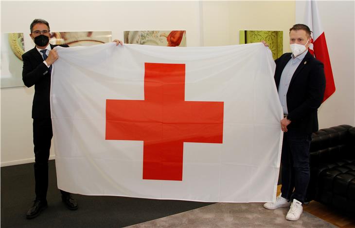 LH Arno Kompatscher (r.) und der Präsident des IRK Südtirol Manuel Pallua: Flagge als Zeichen für das gemeinsame Ziel, die Solidarität und das friedliche Zusammenleben zu stärken. (Foto: LPA/gst)