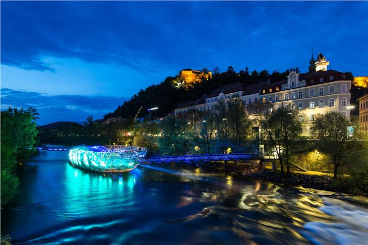 Sehenswürdigkeiten, wie die Murinsel in der Steirischen Hauptstadt Graz, werden am 17. Mai in Blau und Grün beleuchtet, um auf die Krankheit Neurofibromatose aufmerksam zu machen. (Foto: Facebook/NF Kinder)